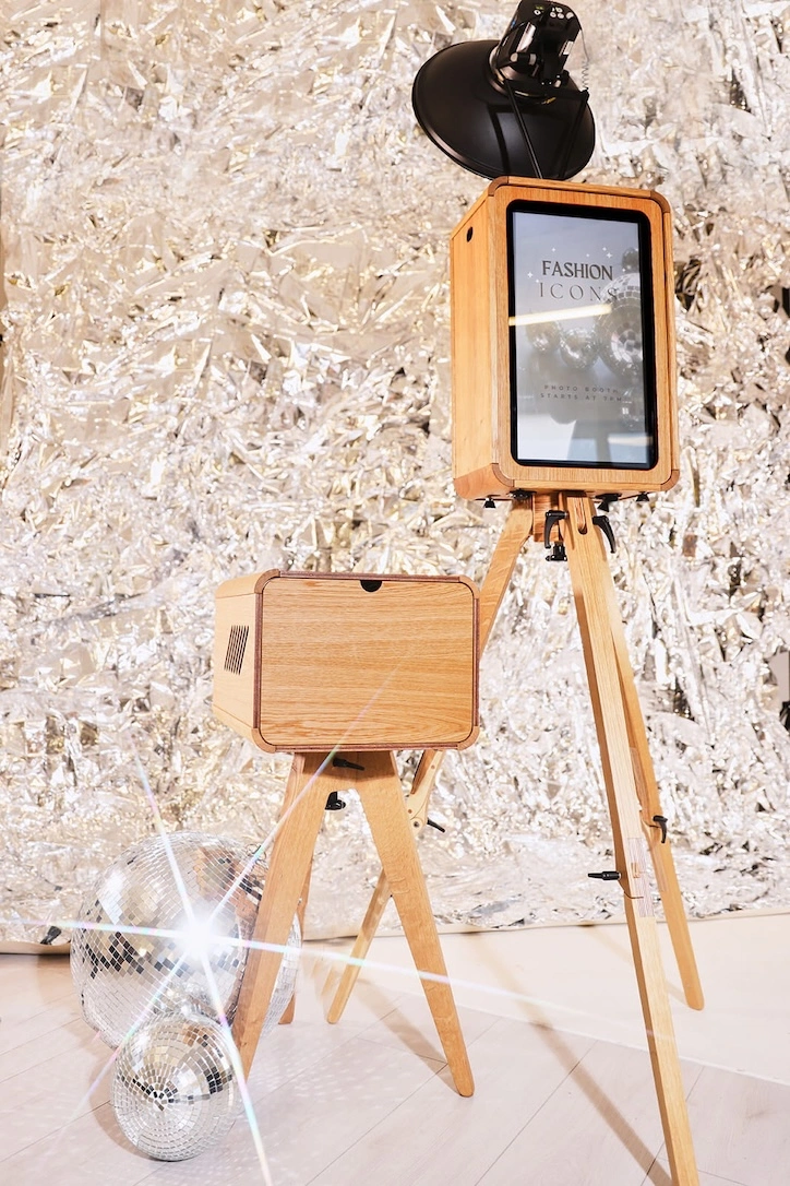 A sophisticated vintage-style wooden photo booth with a beauty dish flash on a tripod stand, set against a sparkling silver sequin backdrop for a London event.